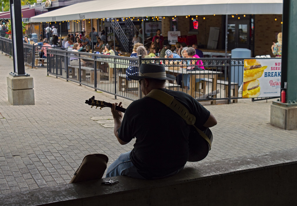 A musician busking outdoors with a guitar